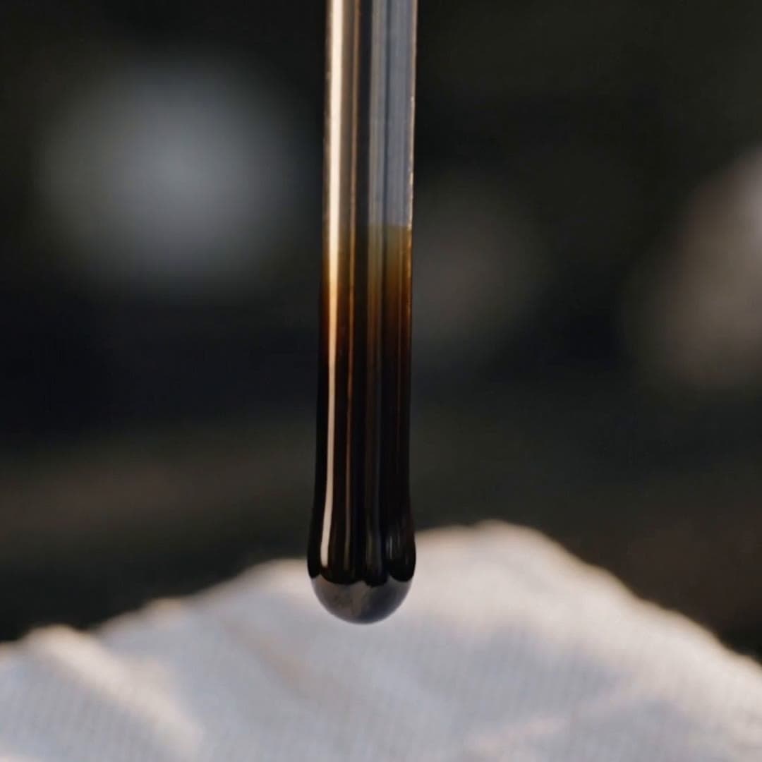 Oil dipstick with dark oil dripping onto a white cloth